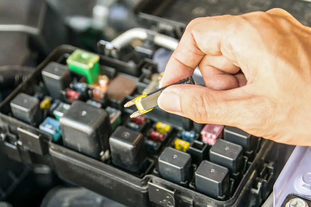 car mechanic checking fuse.